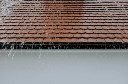Rainwater overflowing from a residential roof during heavy rainfall, highlighting the importance of proper drainage and gutter systems in Clovis, NM.